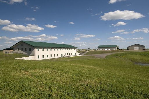 Pre-engineered metal buildings surrounded by green-grass farm land.